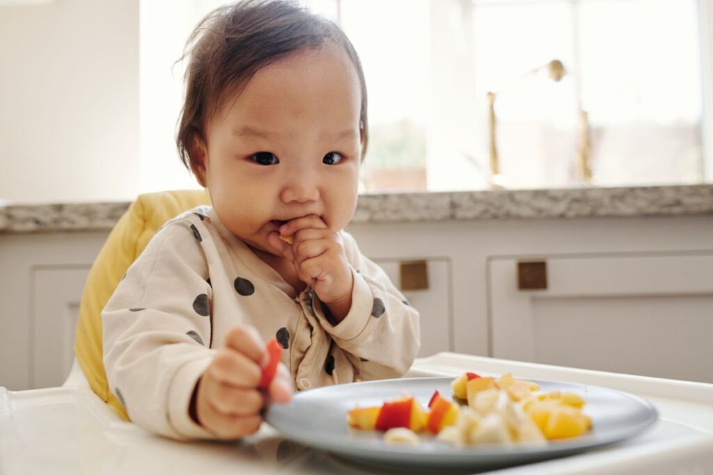 Bebê de aproximadamente 6 meses experimentando os primeiros alimentos sólidos