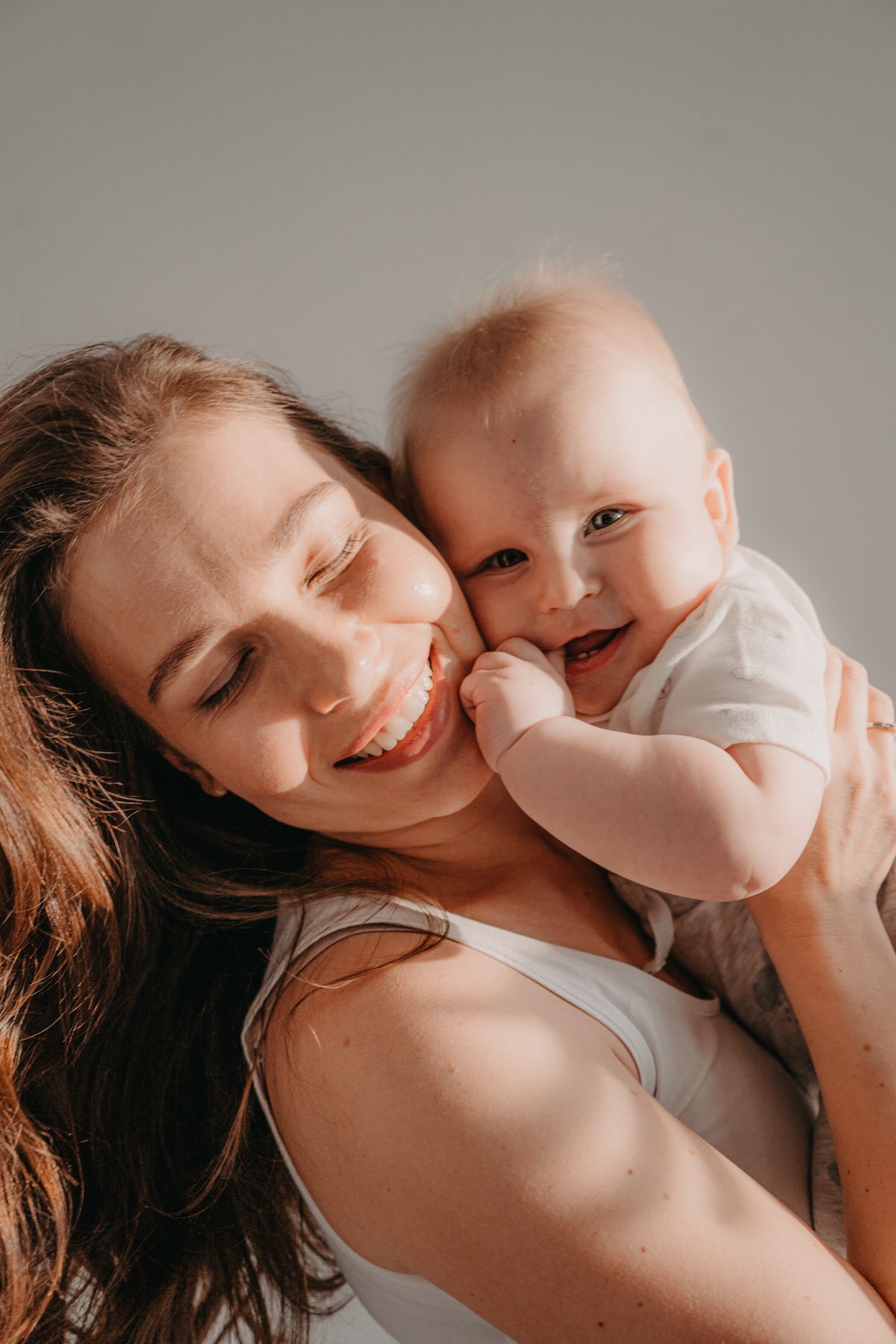 Mãe sorrindo e abraçando o bebê com calma